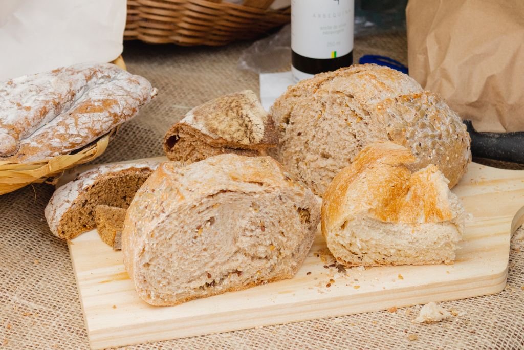 A variety of fresh artisan breads on a wooden board, displayed with a rustic style.